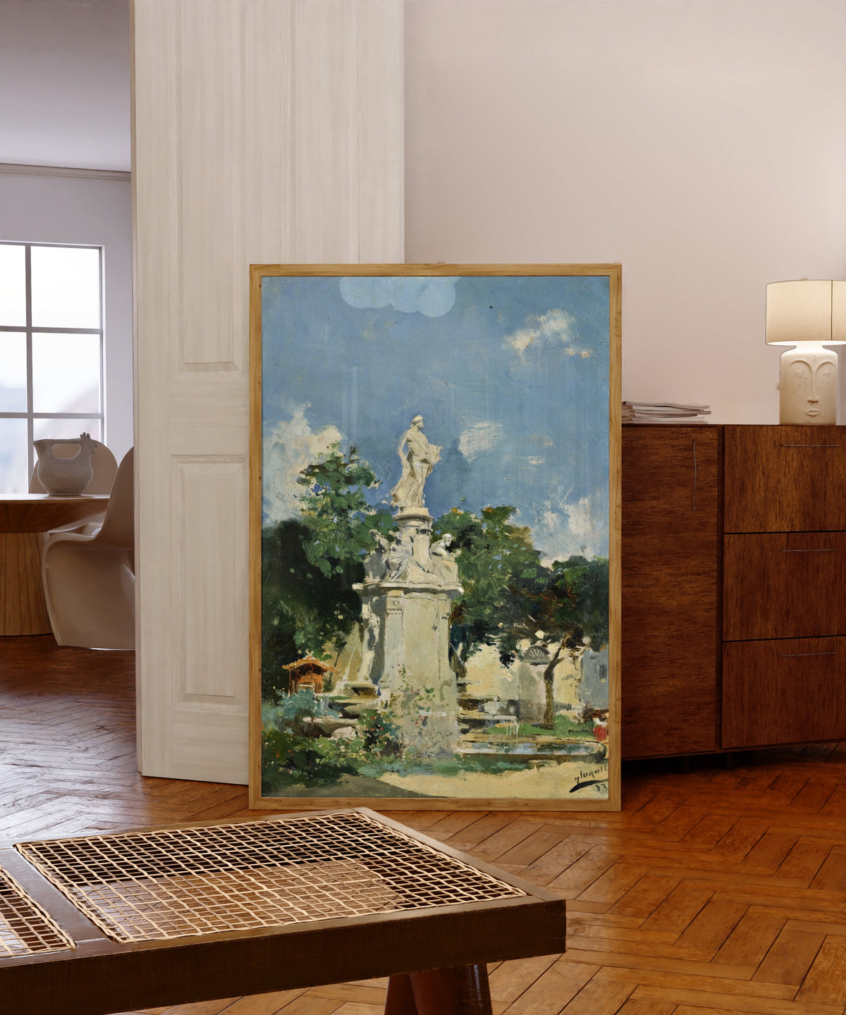 Framed art print of The Fountain of Apollo, Madrid by Joaquín Sorolla, in a light wood frame leaning in a warm room with a parquet floor