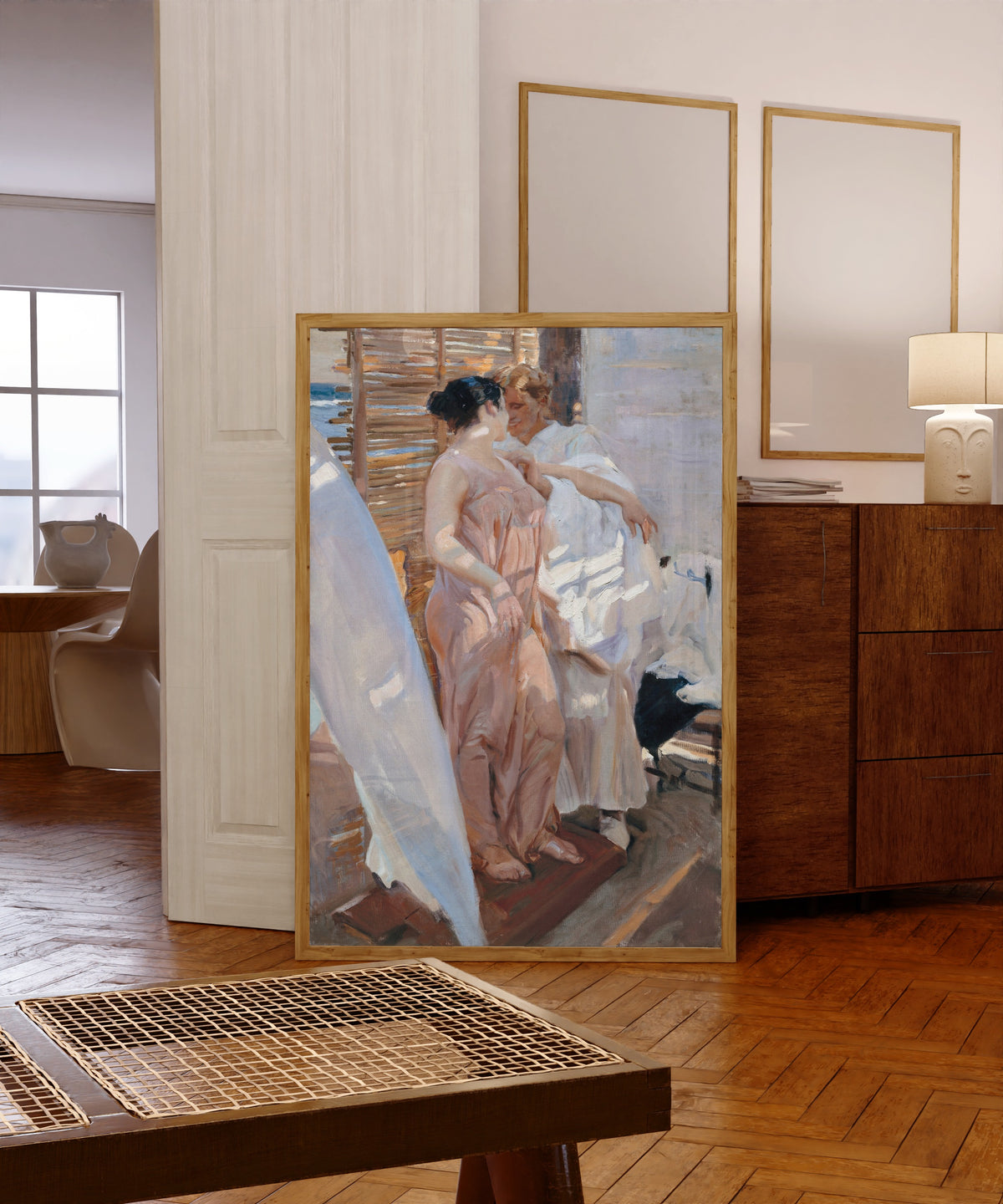Framed art print of The Pink Robe (After the Bath) by Joaquín Sorolla, in a light wood frame leaning in a warm room with a parquet floor