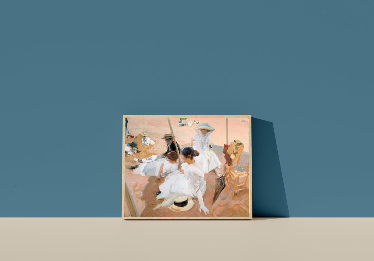 Framed art print of Under the Awning, Zarauz by Joaquín Sorolla, in a light wood frame leaning on a blue wall
