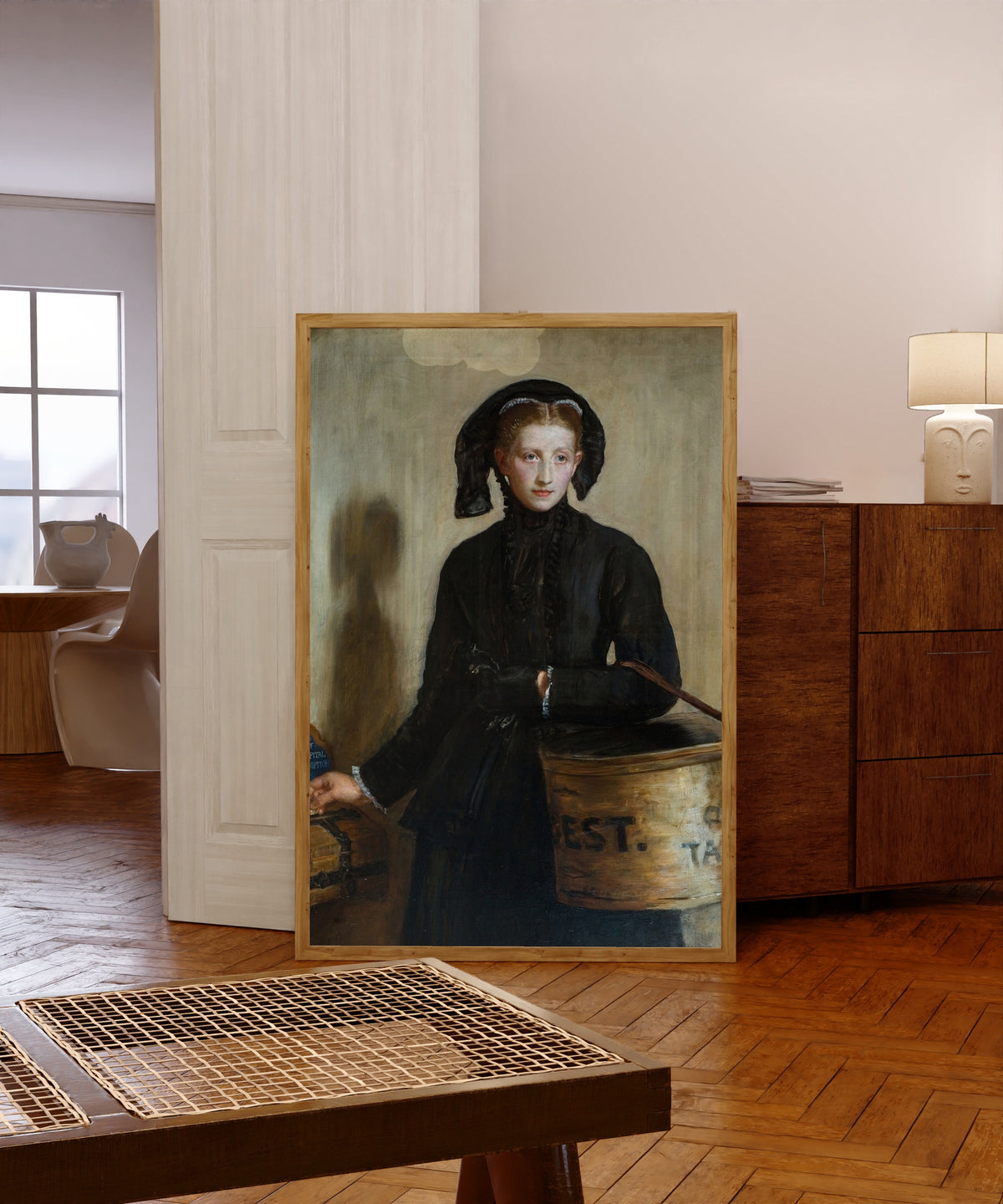 Framed art print of A Widow's Mite by John Everett Millais, in a light wood frame leaning in a warm room with a parquet floor
