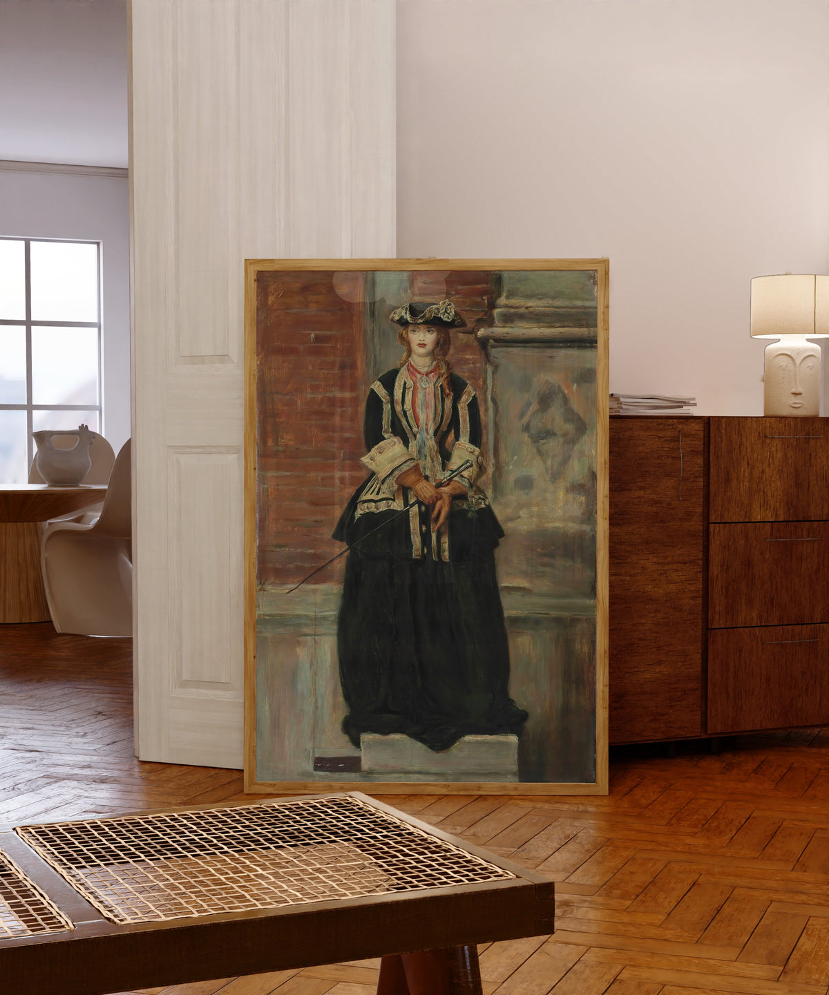 Framed art print of Charlie Is My Darling by John Everett Millais, in a light wood frame leaning in a warm room with a parquet floor