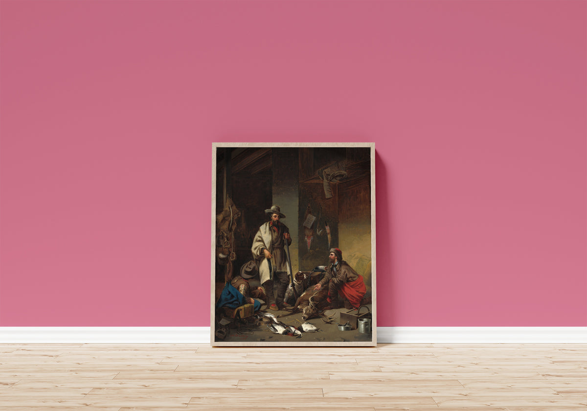 Framed art print of The Trapper's Cabin by John Mix Stanley, in a light wood frame leaning on a pink wall above a wooden floor