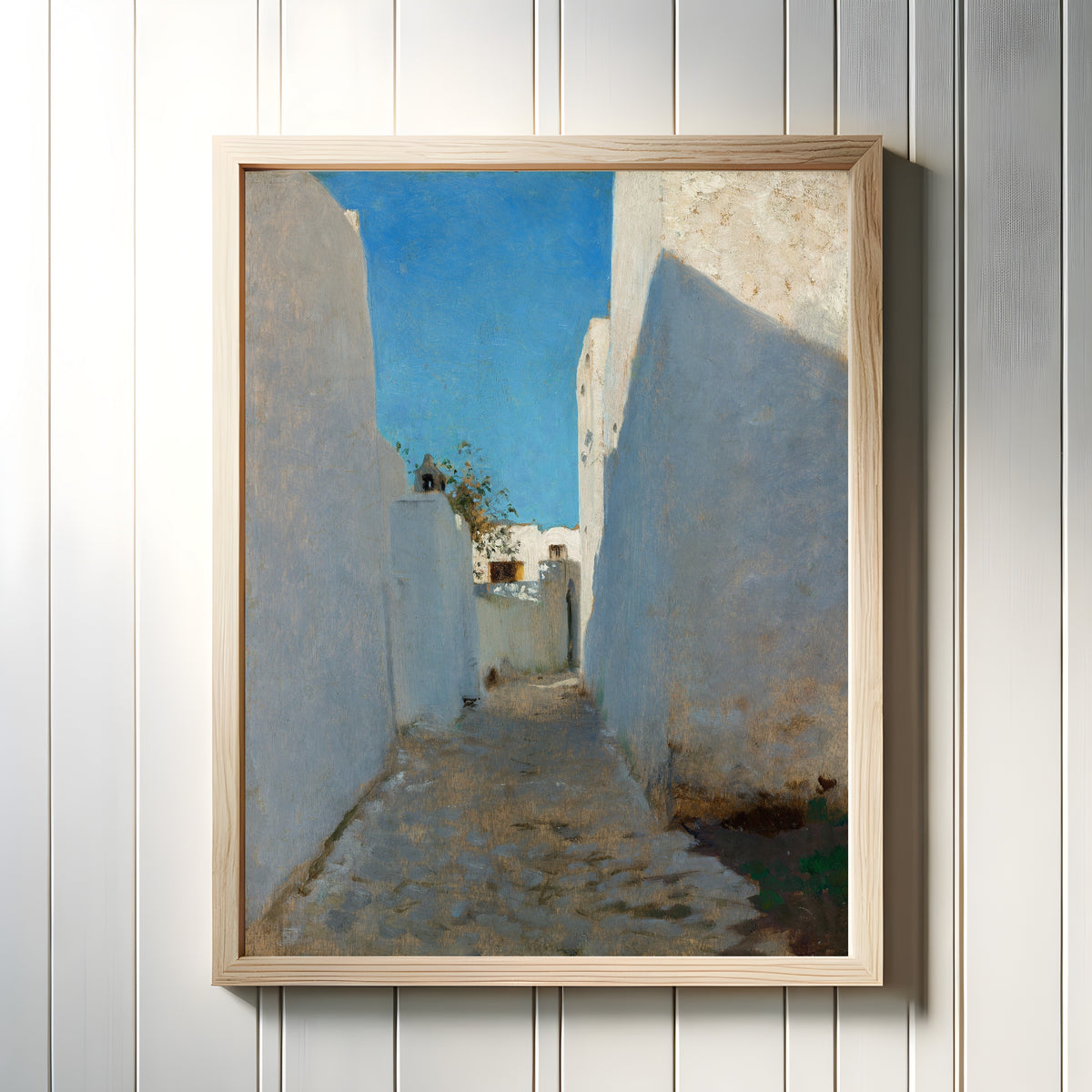 Framed art print of A Moroccan Street Scene by John Singer Sargent, in a light wood frame on a white panelled wall