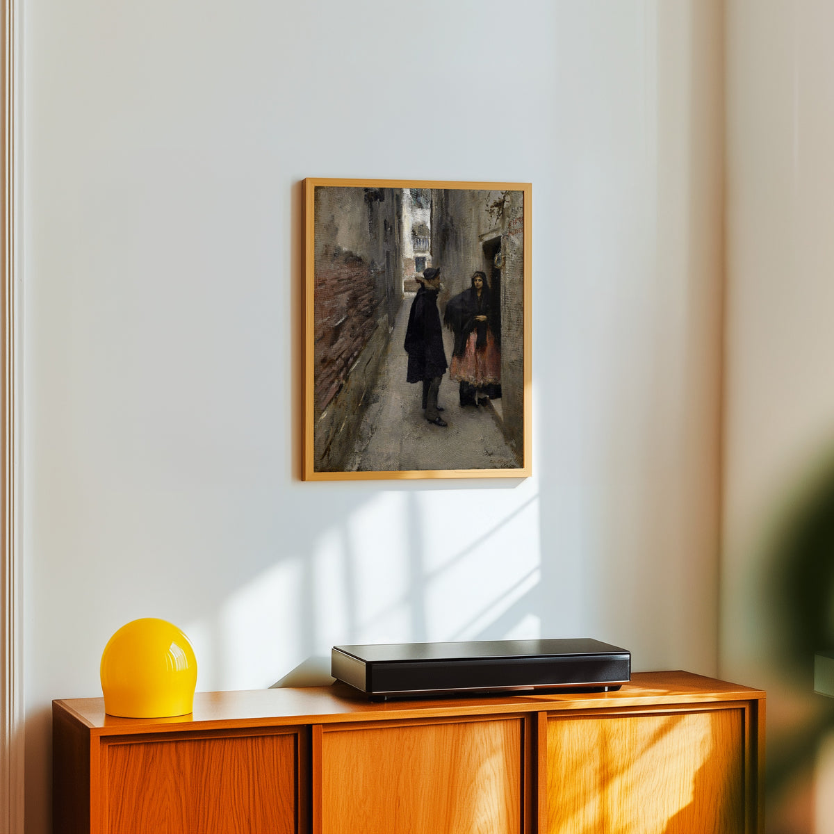 Framed art print of A Street in Venice by John Singer Sargent, in a light wood frame on a white wall above an orange sideboard
