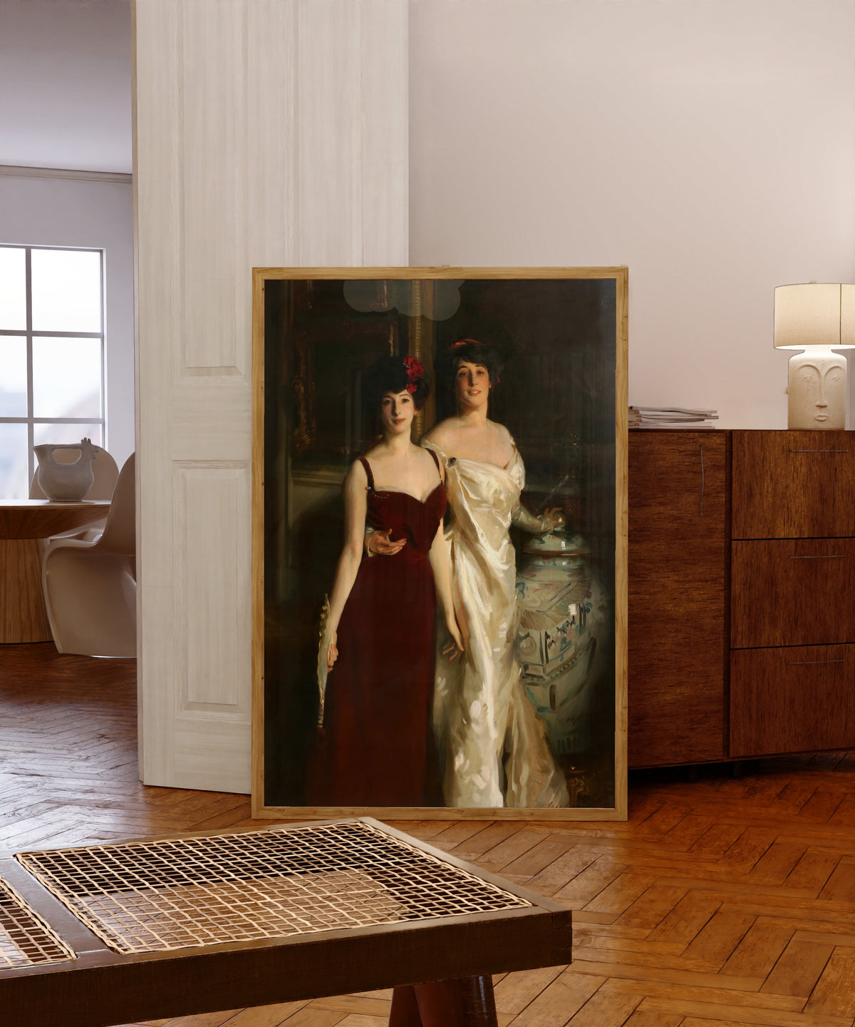 Framed art print of Ena and Betty, Daughters of Asher and Mrs.… by John Singer Sargent, in a light wood frame leaning in a warm room with a parquet floor