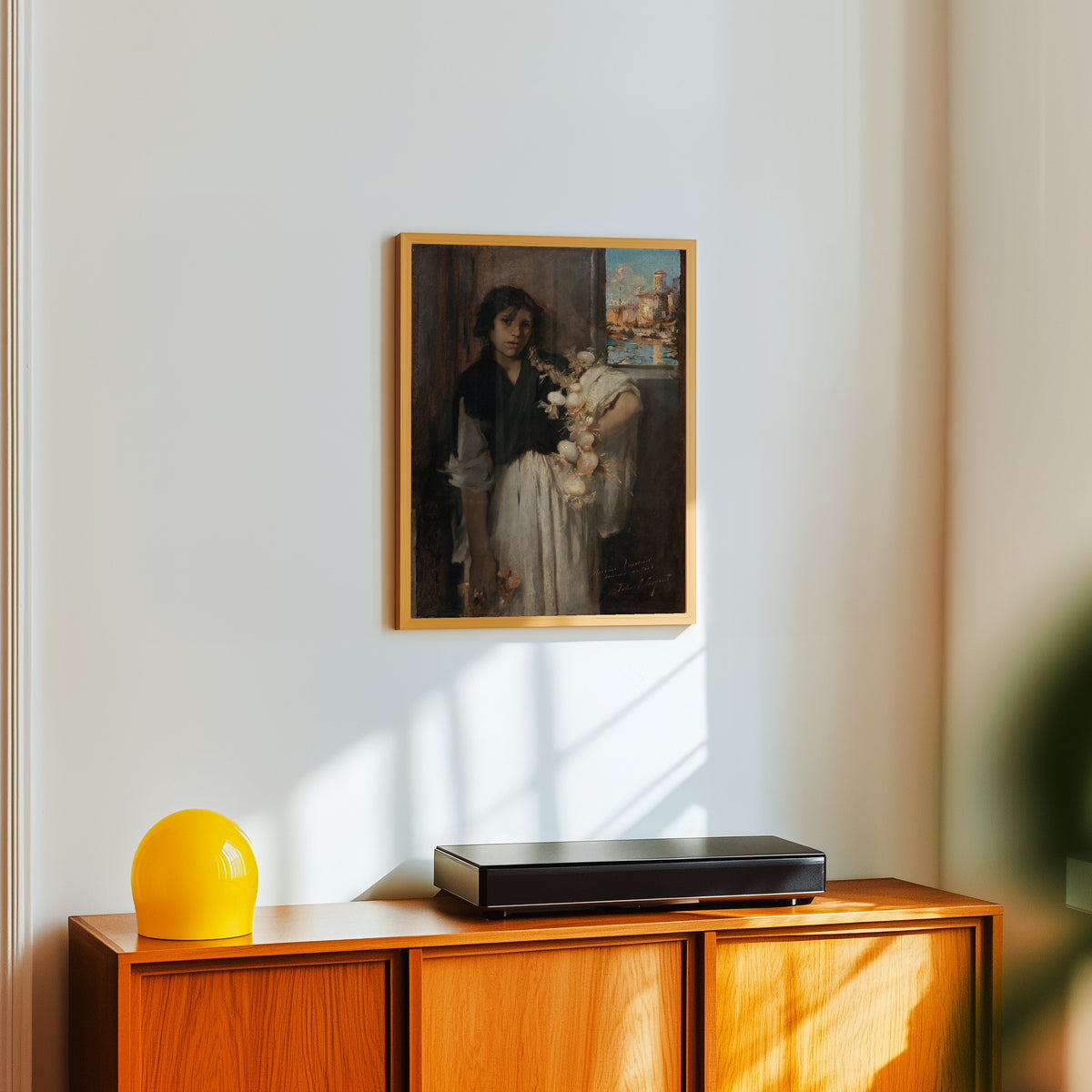 Framed art print of Venetian Onion Seller by John Singer Sargent, in a light wood frame on a white wall above an orange sideboard