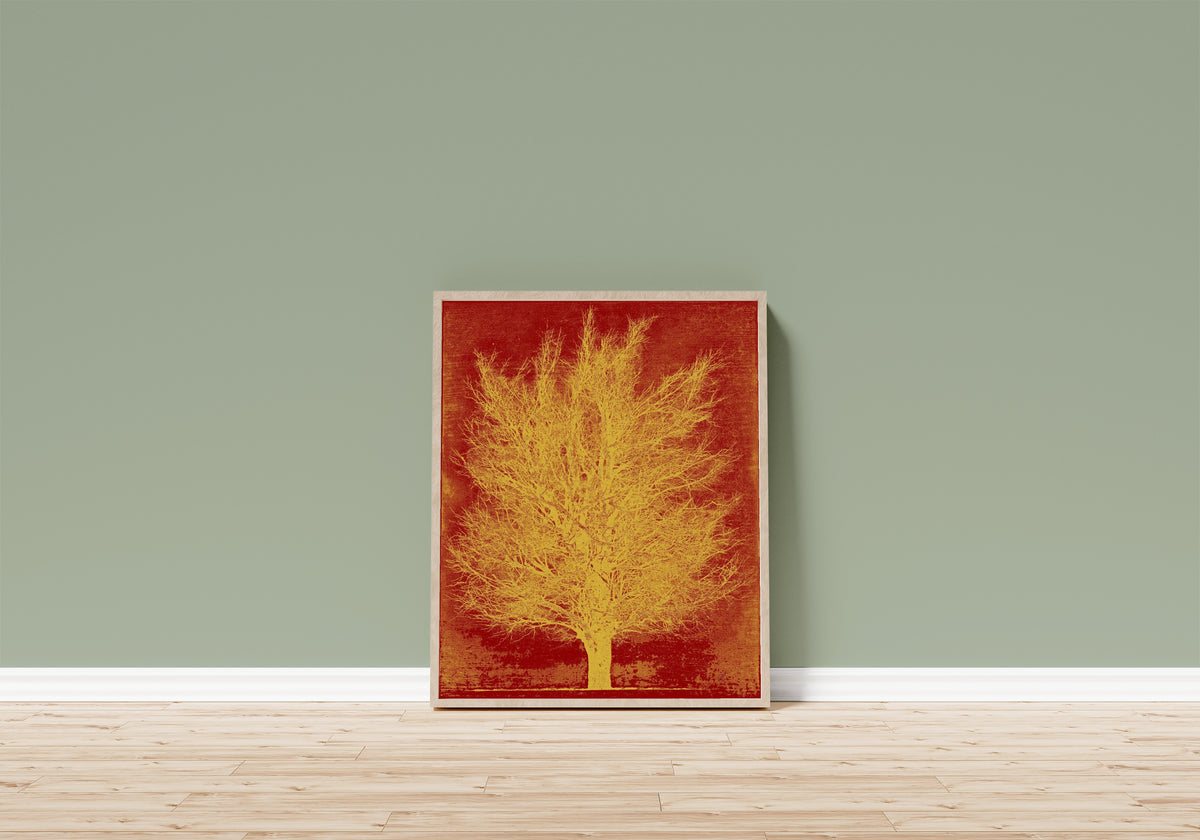 Framed art print of Gold Tree by Joichi Hoshi, in a light wood frame leaning on a sage green wall above a wooden floor
