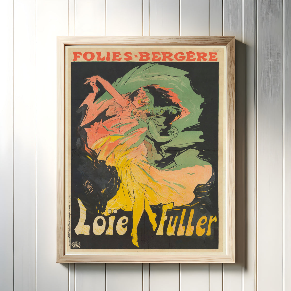 Framed art print of Folies-Bergère, Loïe Fuller by Jules Chéret, in a light wood frame on a white panelled wall