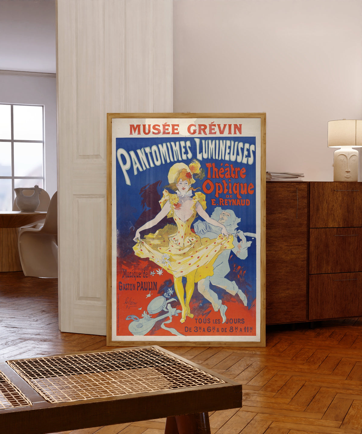 Framed art print of Pantomimes lumineuses by Jules Chéret, in a light wood frame leaning in a warm room with a parquet floor