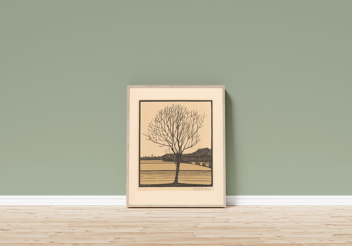 Framed art print of Bare Tree by Water by Julie de Graag, in a light wood frame leaning on a sage green wall above a wooden floor