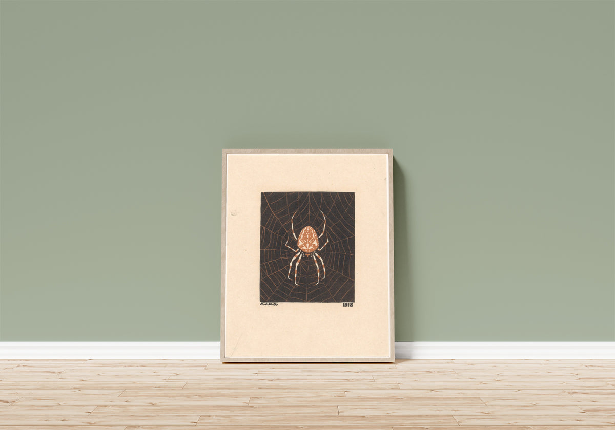 Framed art print of Spider in web by Julie de Graag, in a light wood frame leaning on a sage green wall above a wooden floor