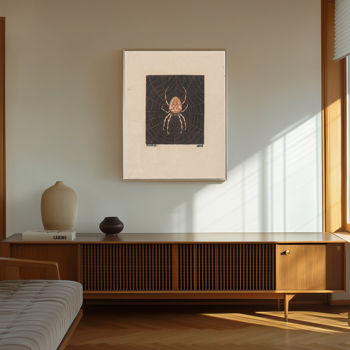 Framed art print of Spider in web by Julie de Graag, in a thin light frame on a sunlit wall above a wooden sideboard