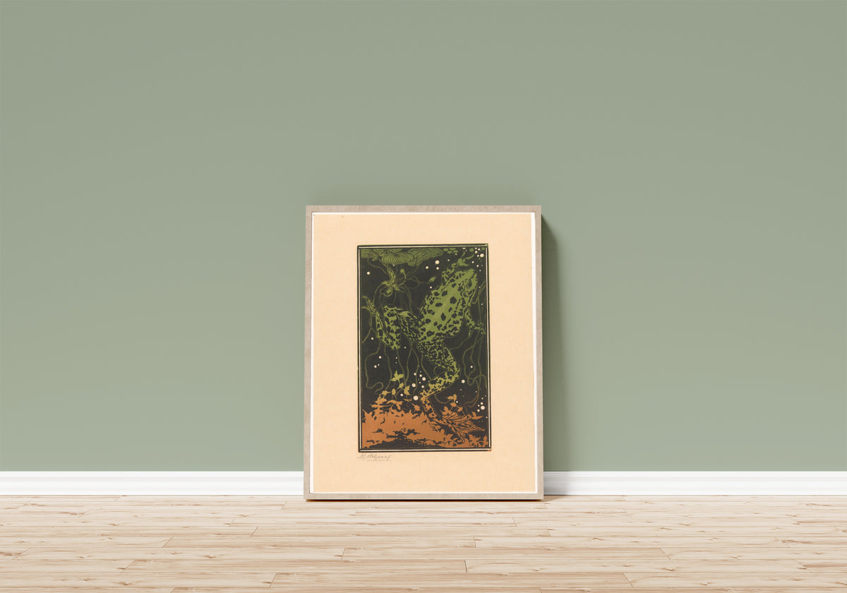 Framed art print of Swimming Frog by Julie de Graag, in a light wood frame leaning on a sage green wall above a wooden floor