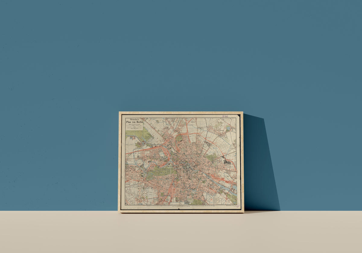 Framed art print of Straube's Plan von Berlin by Julius Straube, in a light wood frame leaning on a blue wall