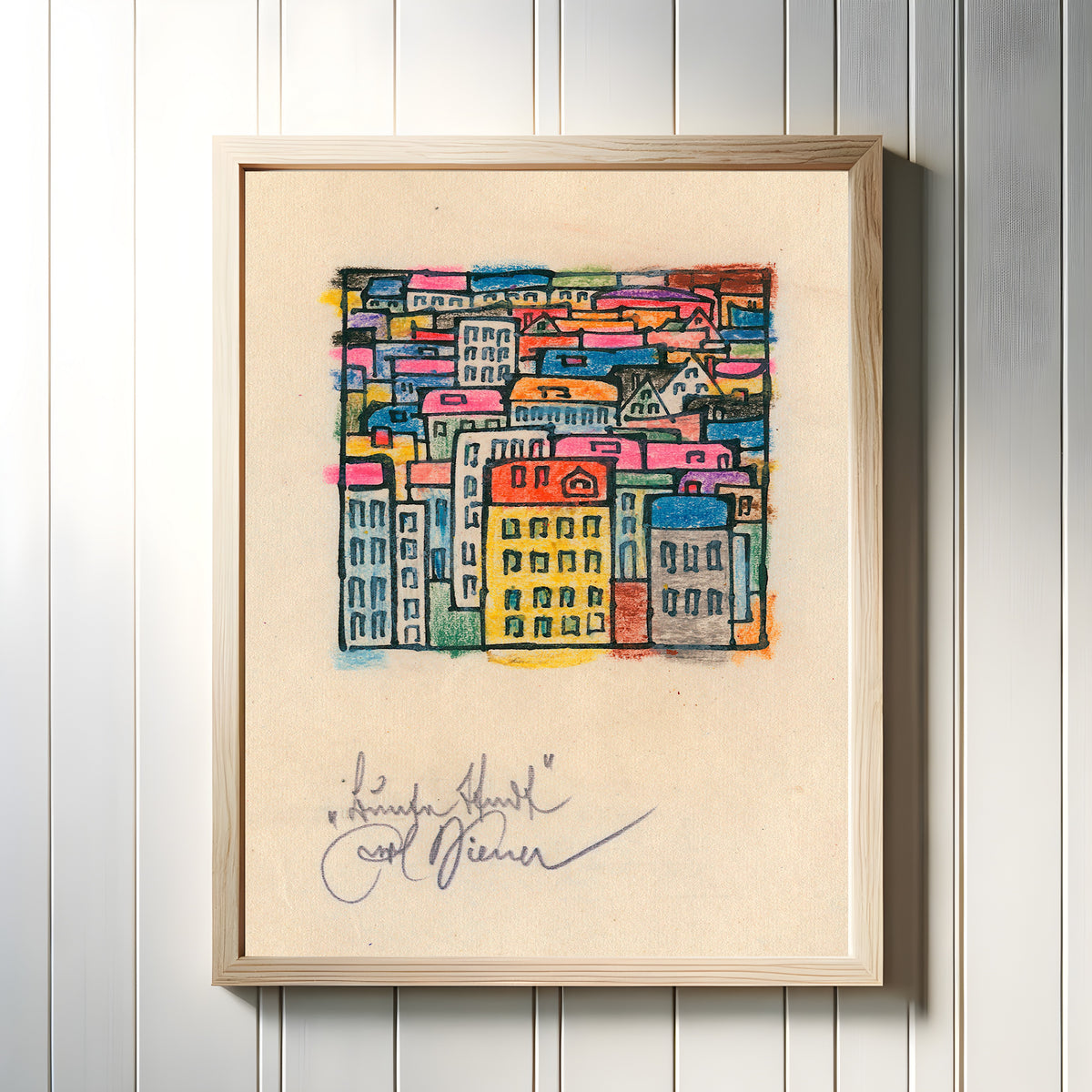 Framed art print of Bunte Stadt (Colourful City) by Karl Wiener, in a light wood frame on a white panelled wall
