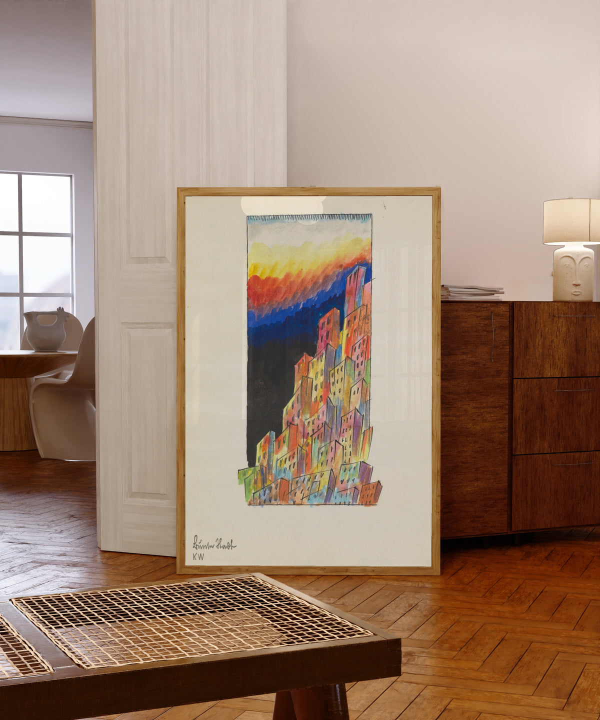 Framed art print of Bunte Stadt (Colourful City, Towers) by Karl Wiener, in a light wood frame leaning in a warm room with a parquet floor