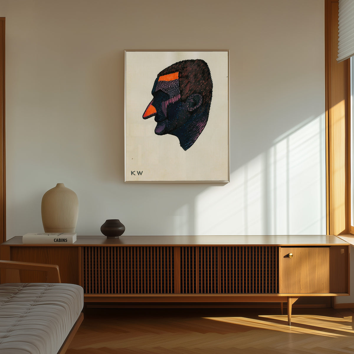 Framed art print of Profile Head Study No. 2 by Karl Wiener, in a thin light frame on a sunlit wall above a wooden sideboard