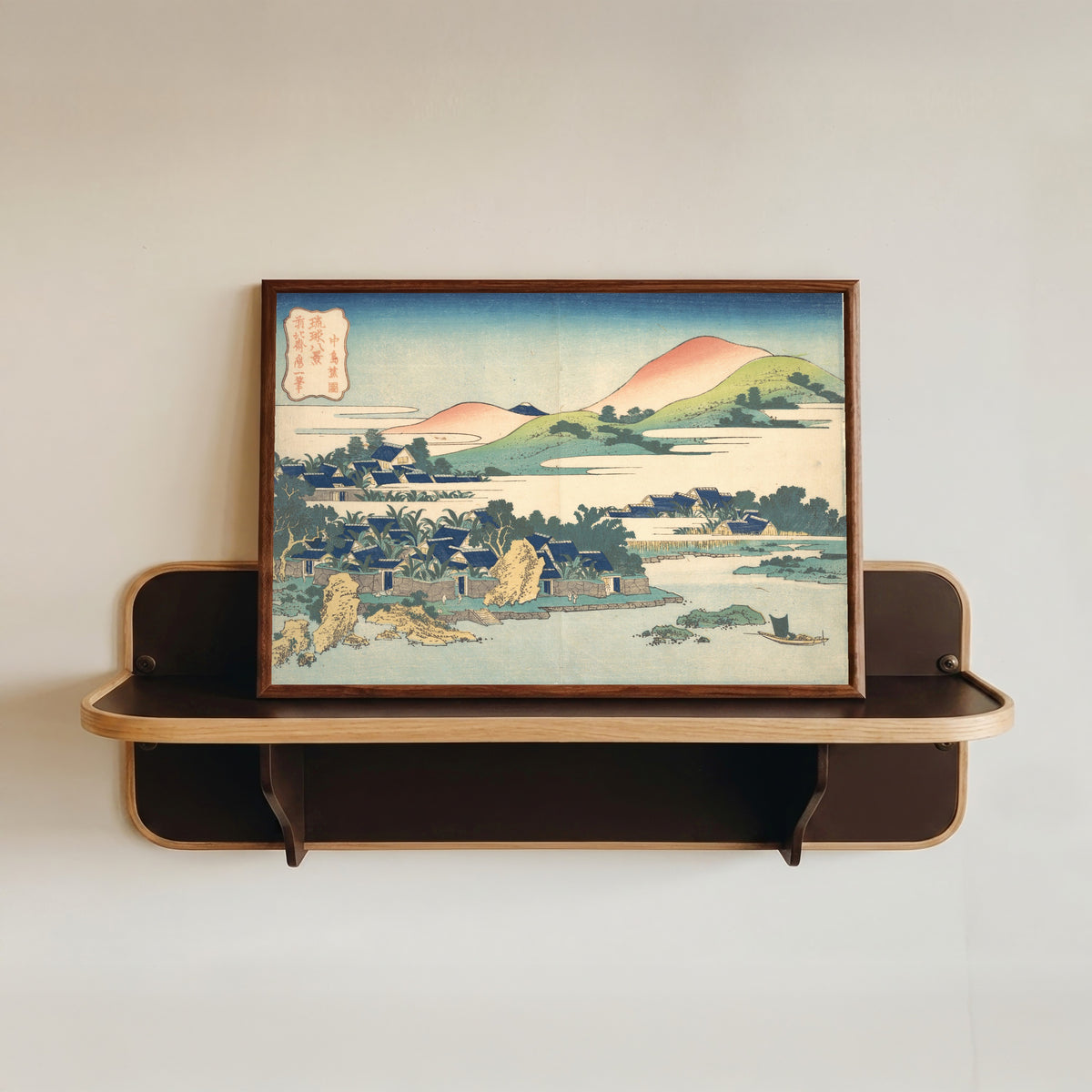 Framed art print of Eight Views of the Ryūkyū Islands: Banana Garden at Nakashima by Katsushika Hokusai, in a dark wood frame resting on a wall shelf