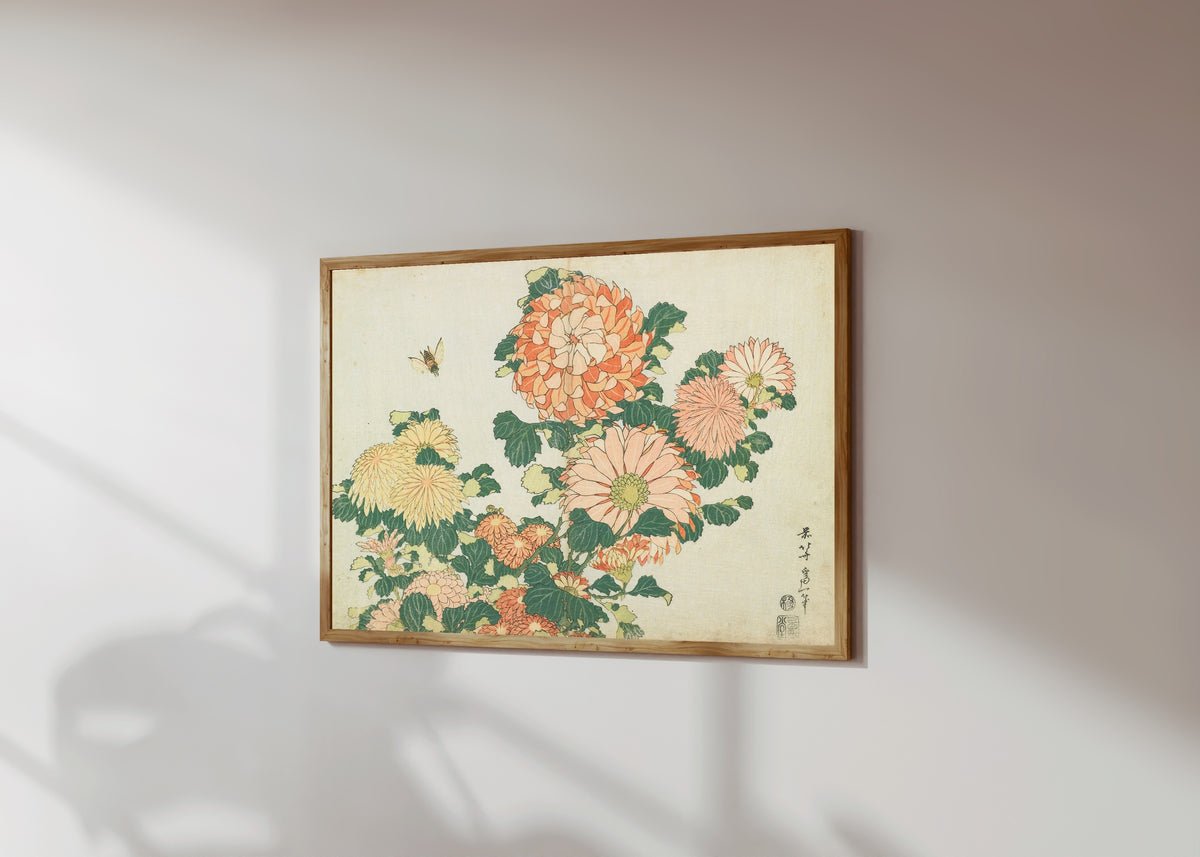 Framed art print of Large Flowers: Chrysanthemums and Horsefly by Katsushika Hokusai, in a light wood frame on a sunlit white wall, seen at a slight angle