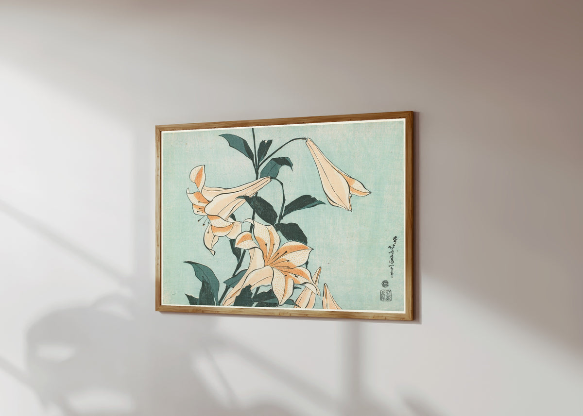 Framed art print of Large Flowers: Lilies by Katsushika Hokusai, in a light wood frame on a sunlit white wall, seen at a slight angle