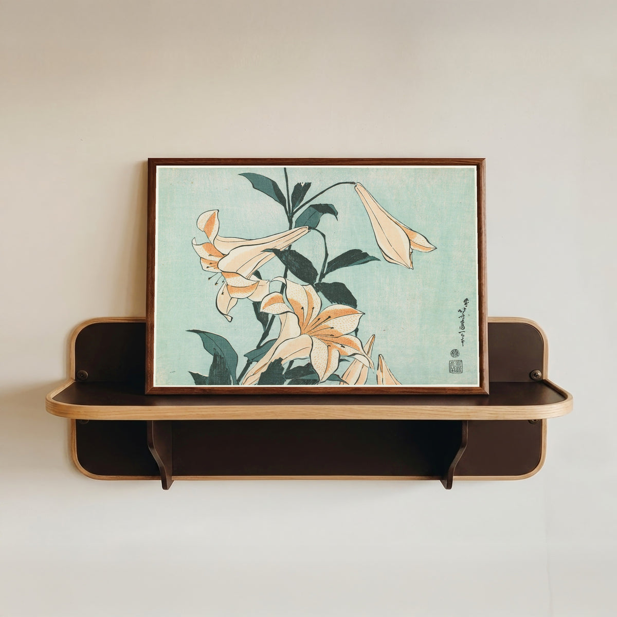 Framed art print of Large Flowers: Lilies by Katsushika Hokusai, in a dark wood frame resting on a wall shelf