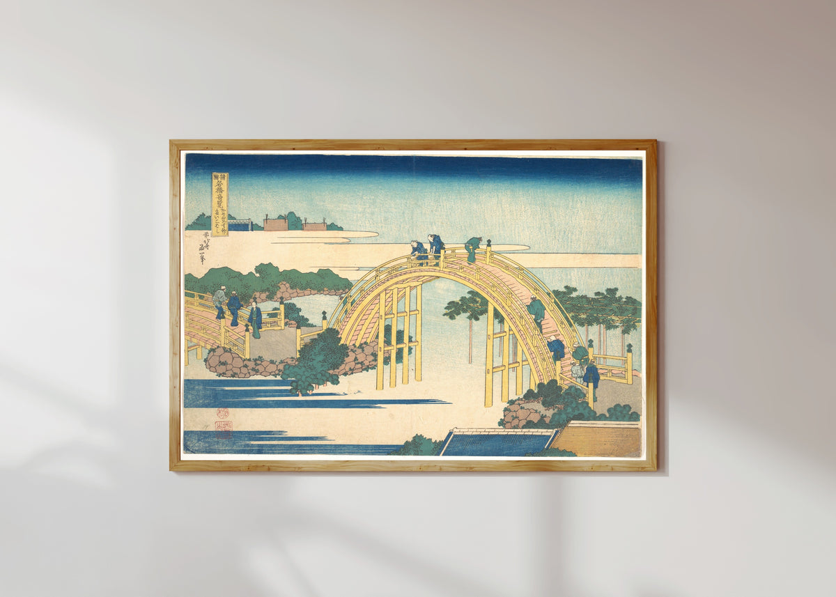 Framed art print of Remarkable Views of Bridges in Various Provinces: The Arched Bridge at… by Katsushika Hokusai, in a light wood frame on a sunlit white wall