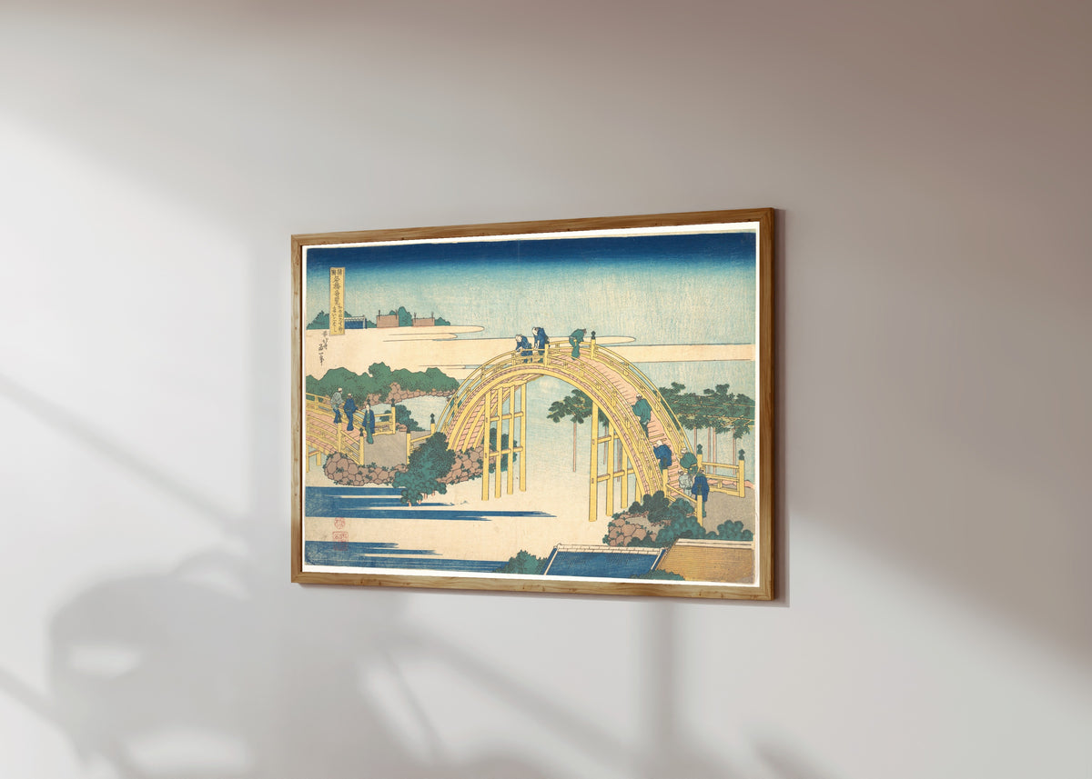 Framed art print of Remarkable Views of Bridges in Various… by Katsushika Hokusai, in a light wood frame on a sunlit white wall, seen at a slight angle