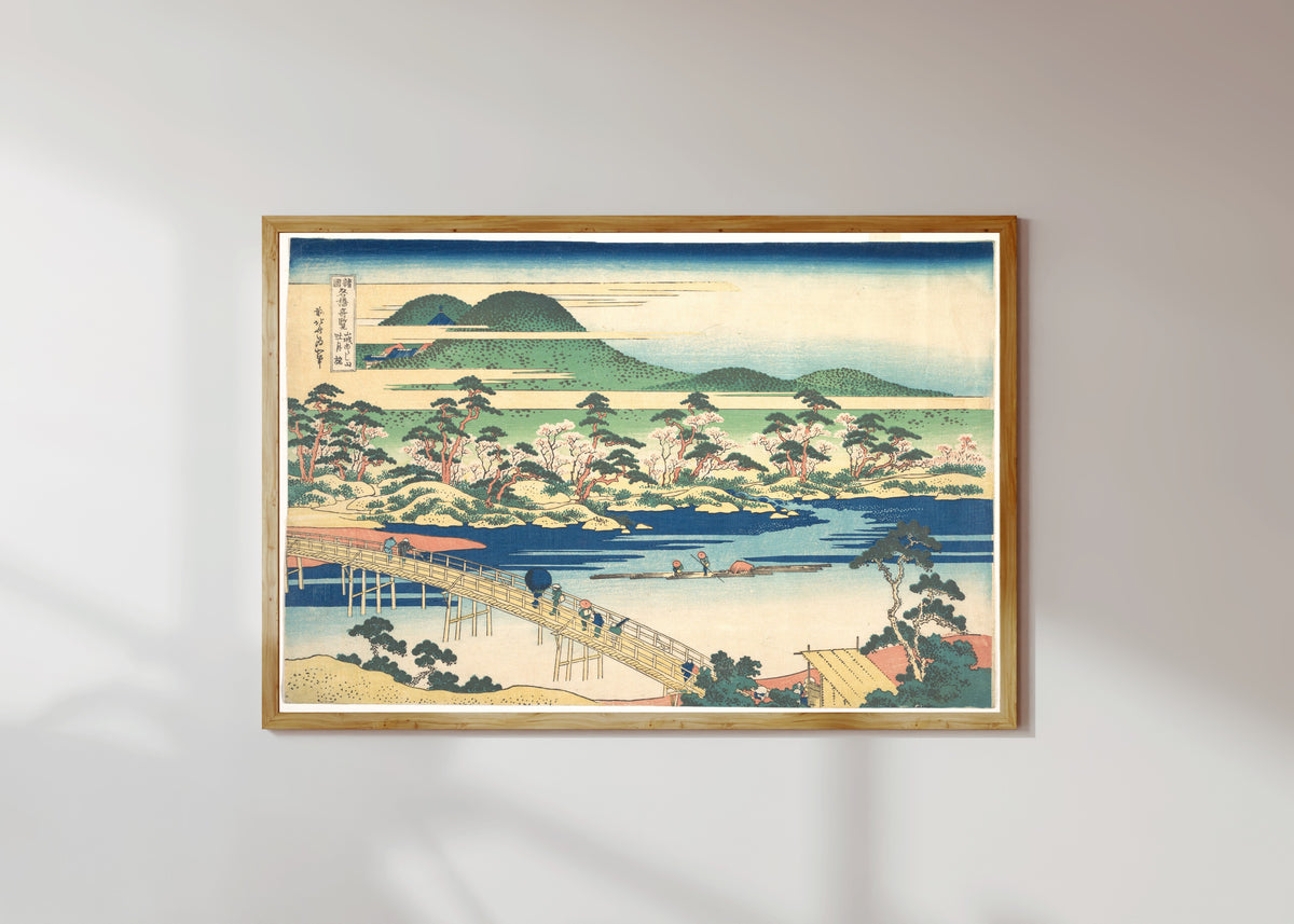 Framed art print of Remarkable Views of Bridges in Various Provinces: Togetsu Bridge at… by Katsushika Hokusai, in a light wood frame on a sunlit white wall