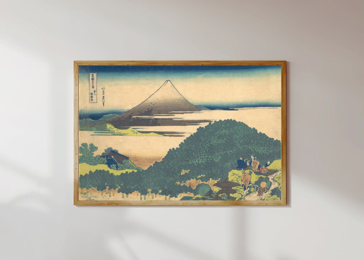 Framed art print of Thirty-six Views of Mount Fuji: Cushion Pine at Aoyama by Katsushika Hokusai, in a light wood frame on a sunlit white wall