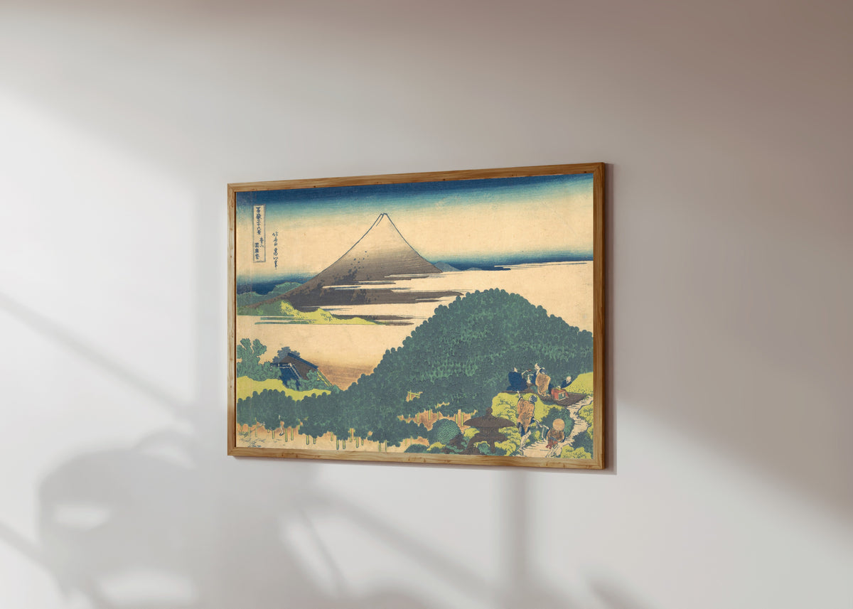 Framed art print of Thirty-six Views of Mount Fuji: Cushion Pine… by Katsushika Hokusai, in a light wood frame on a sunlit white wall, seen at a slight angle