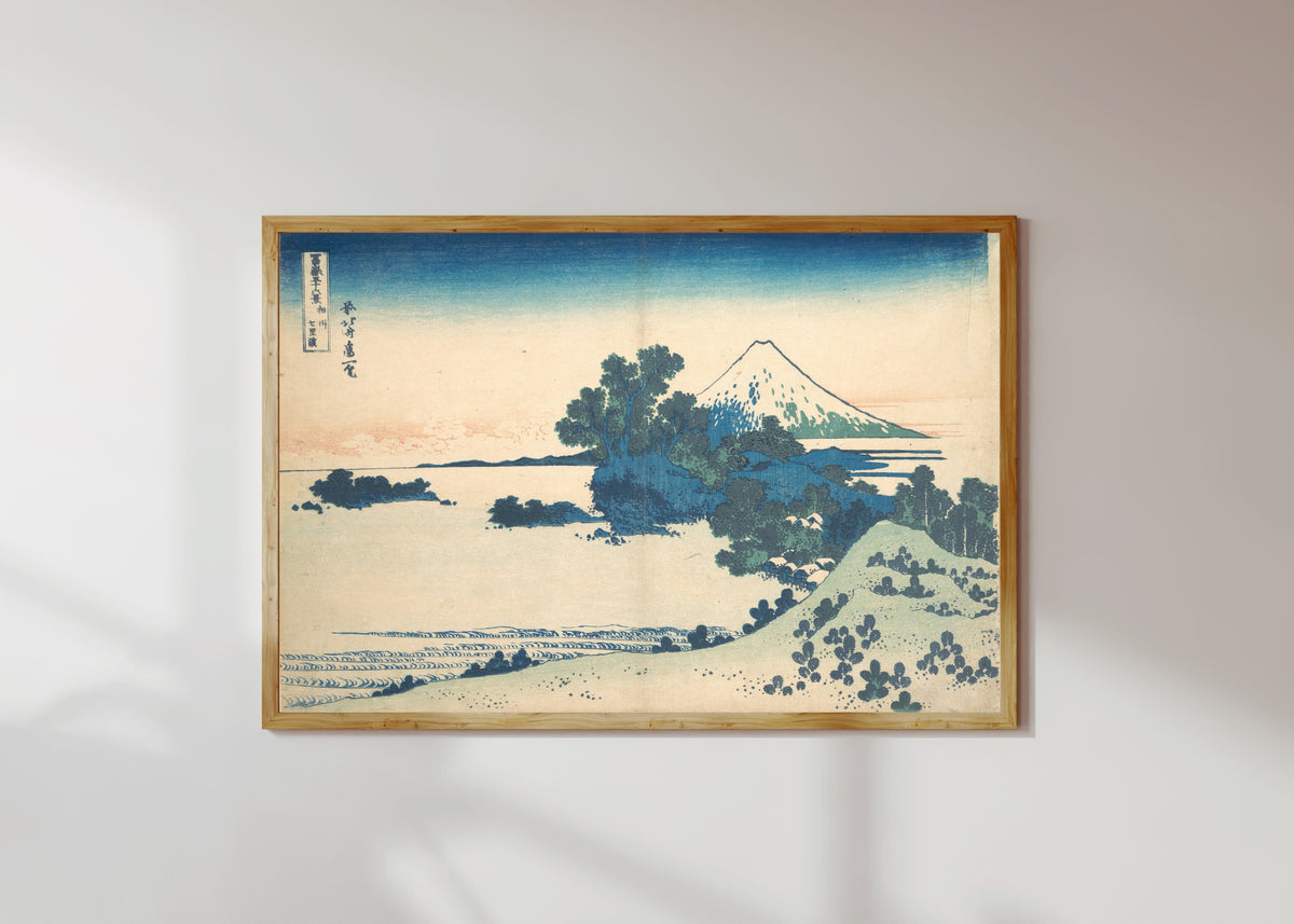 Framed art print of Thirty-six Views of Mount Fuji: Shichirigahama in Sagami Province by Katsushika Hokusai, in a light wood frame on a sunlit white wall