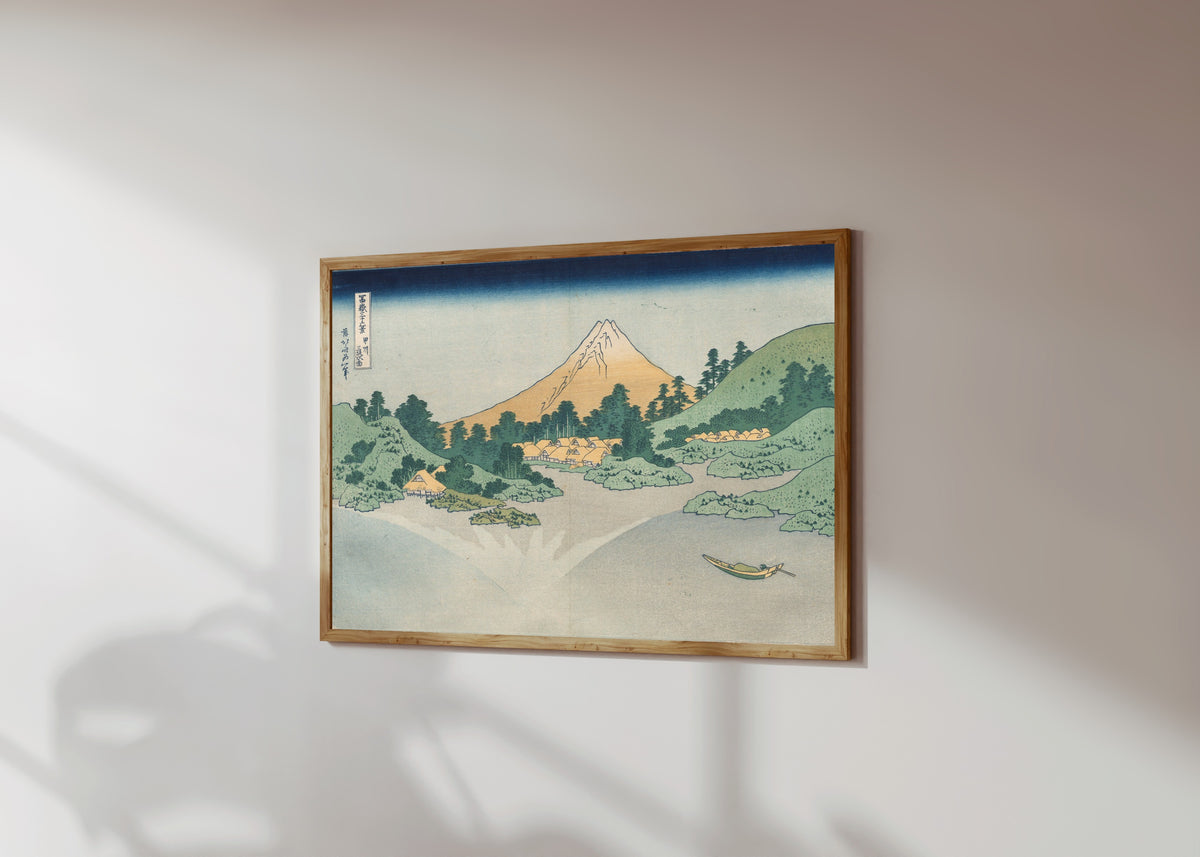 Framed art print of Thirty-six Views of Mount Fuji: The Surface of… by Katsushika Hokusai, in a light wood frame on a sunlit white wall, seen at a slight angle