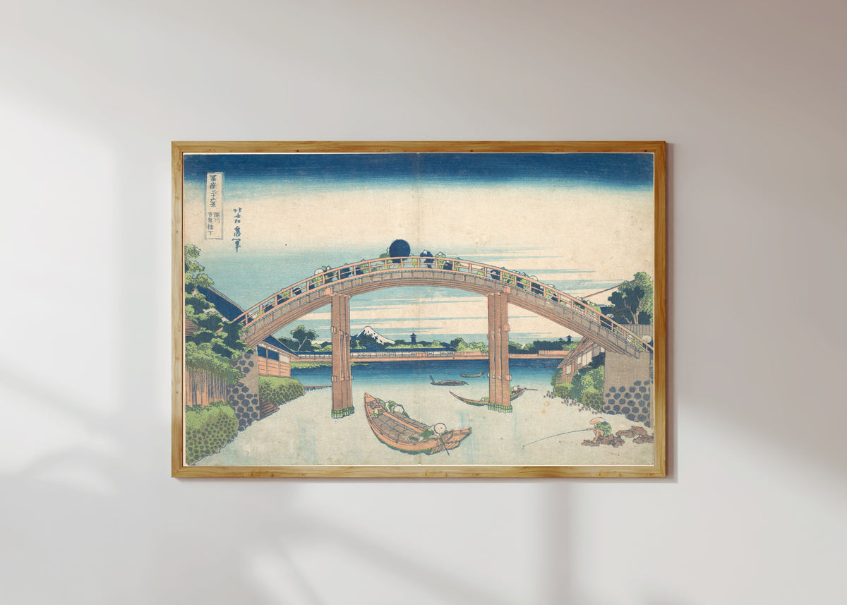 Framed art print of Thirty-six Views of Mount Fuji: Under the Mannen Bridge at Fukagawa by Katsushika Hokusai, in a light wood frame on a sunlit white wall