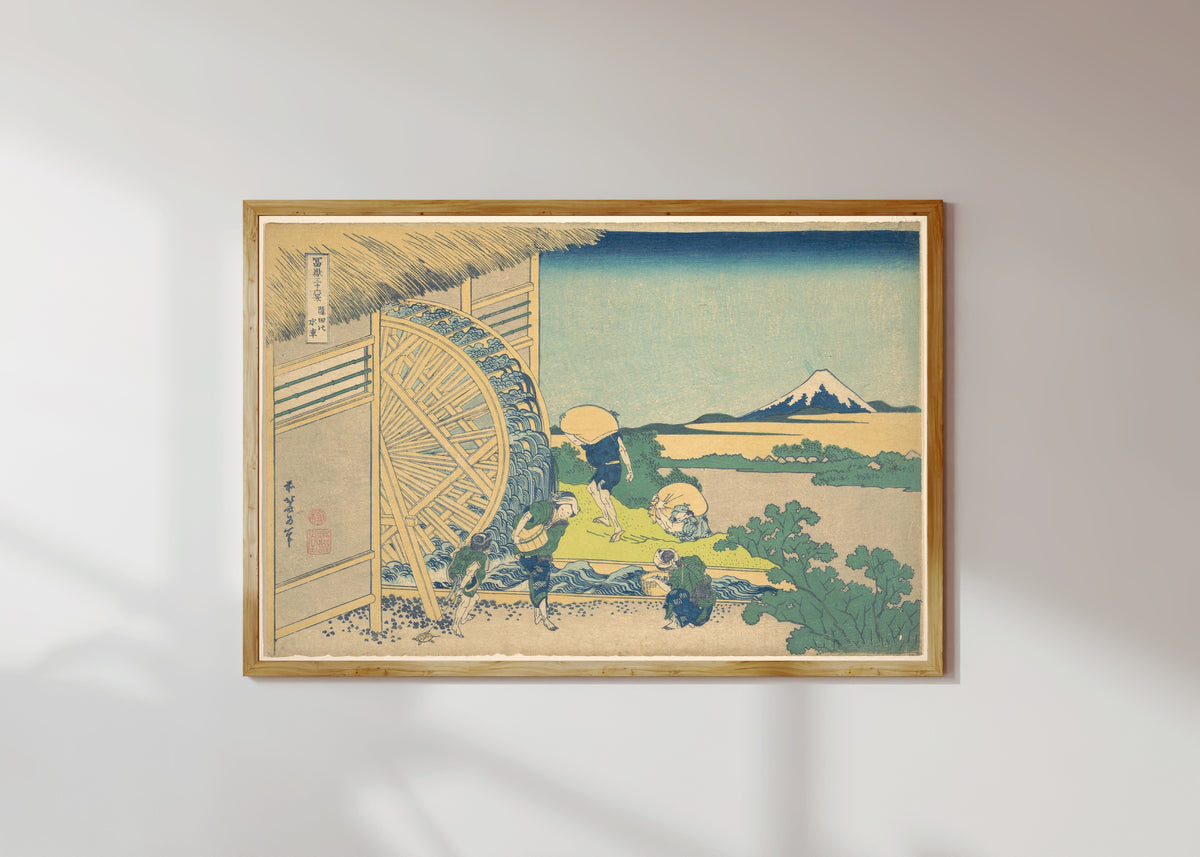 Framed art print of Thirty-six Views of Mount Fuji: Waterwheel at Onden by Katsushika Hokusai, in a light wood frame on a sunlit white wall
