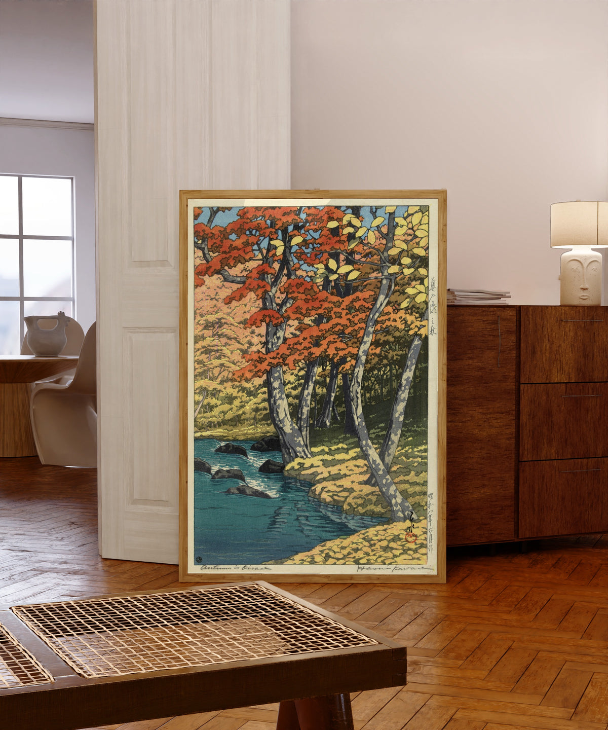 Framed art print of Autumn in the Forest by Kawase Hasui, in a light wood frame leaning in a warm room with a parquet floor
