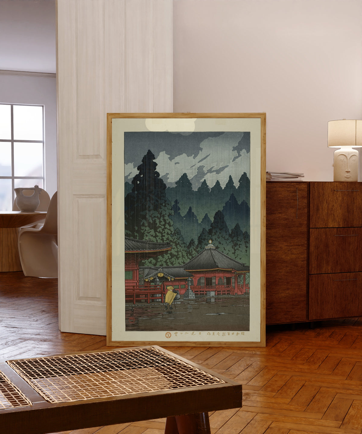 Framed art print of Futatsudo Hall, Nikko by Kawase Hasui, in a light wood frame leaning in a warm room with a parquet floor
