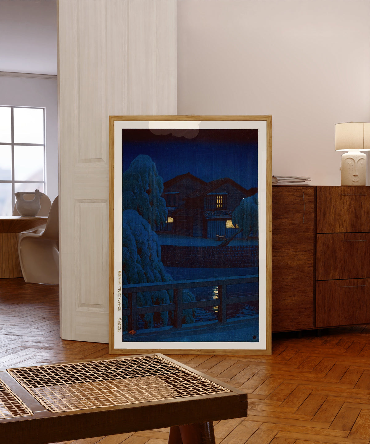 Framed art print of Gosai Canal, Niigata by Kawase Hasui, in a light wood frame leaning in a warm room with a parquet floor