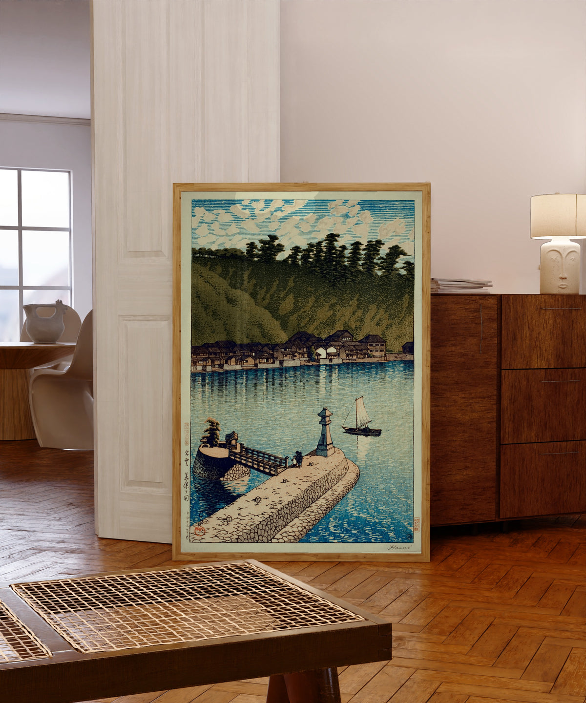 Framed art print of Mihogaseki Bridge by Kawase Hasui, in a light wood frame leaning in a warm room with a parquet floor