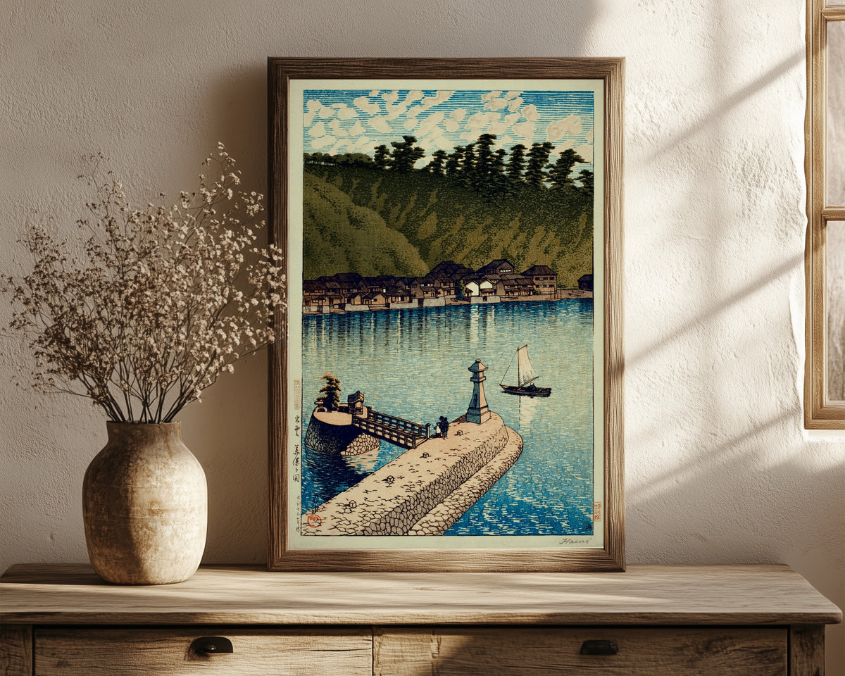 Framed art print of Mihogaseki Bridge by Kawase Hasui, in a dark wood frame leaning on a rustic console beside dried flowers