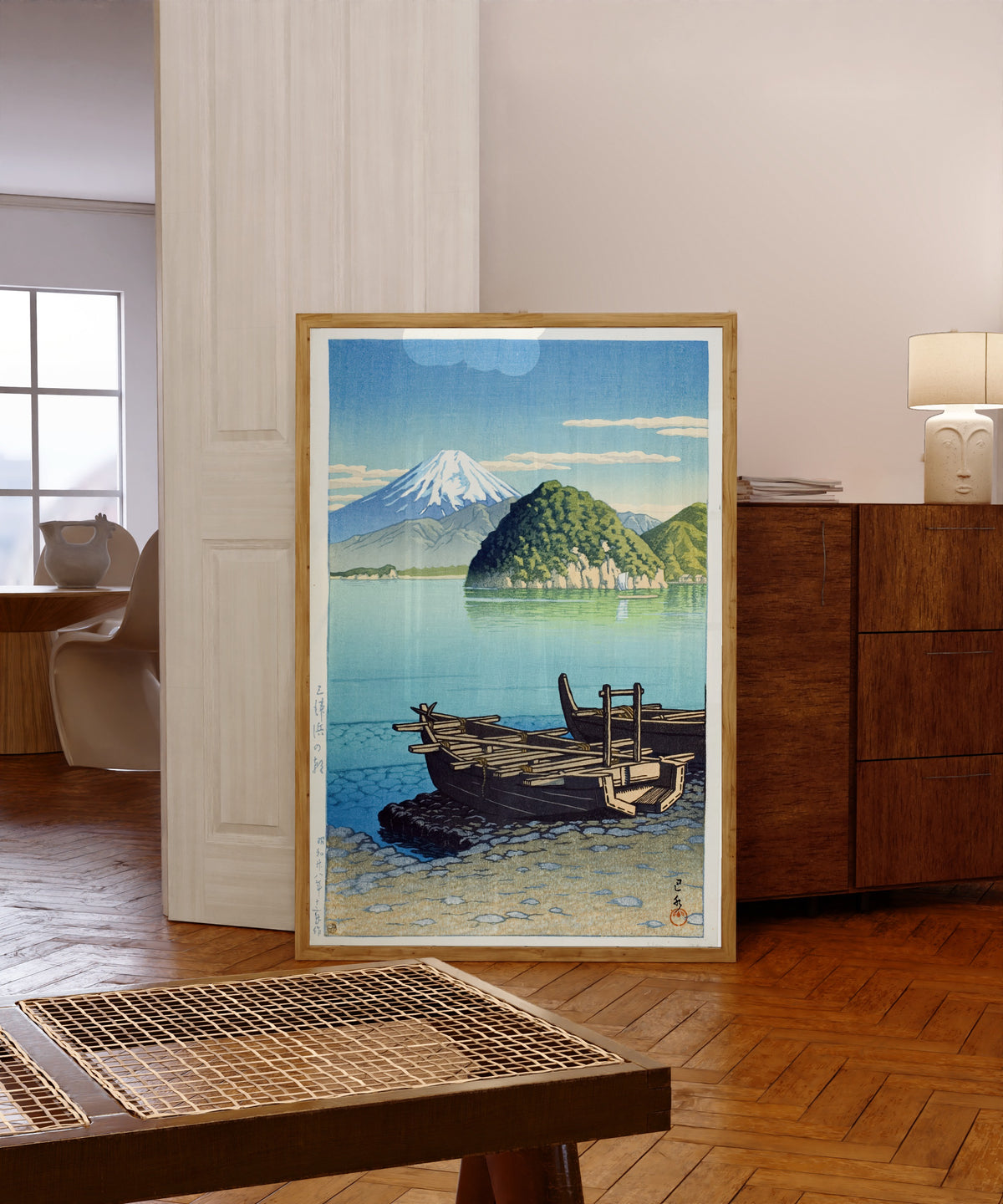 Framed art print of Morning at Miho Beach by Kawase Hasui, in a light wood frame leaning in a warm room with a parquet floor
