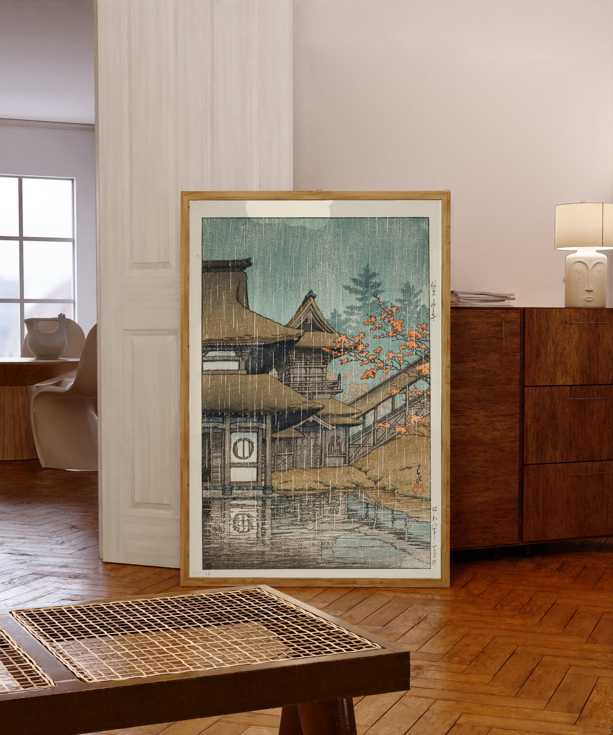 Framed art print of Yamadera Temple in Rain by Kawase Hasui, in a light wood frame leaning in a warm room with a parquet floor