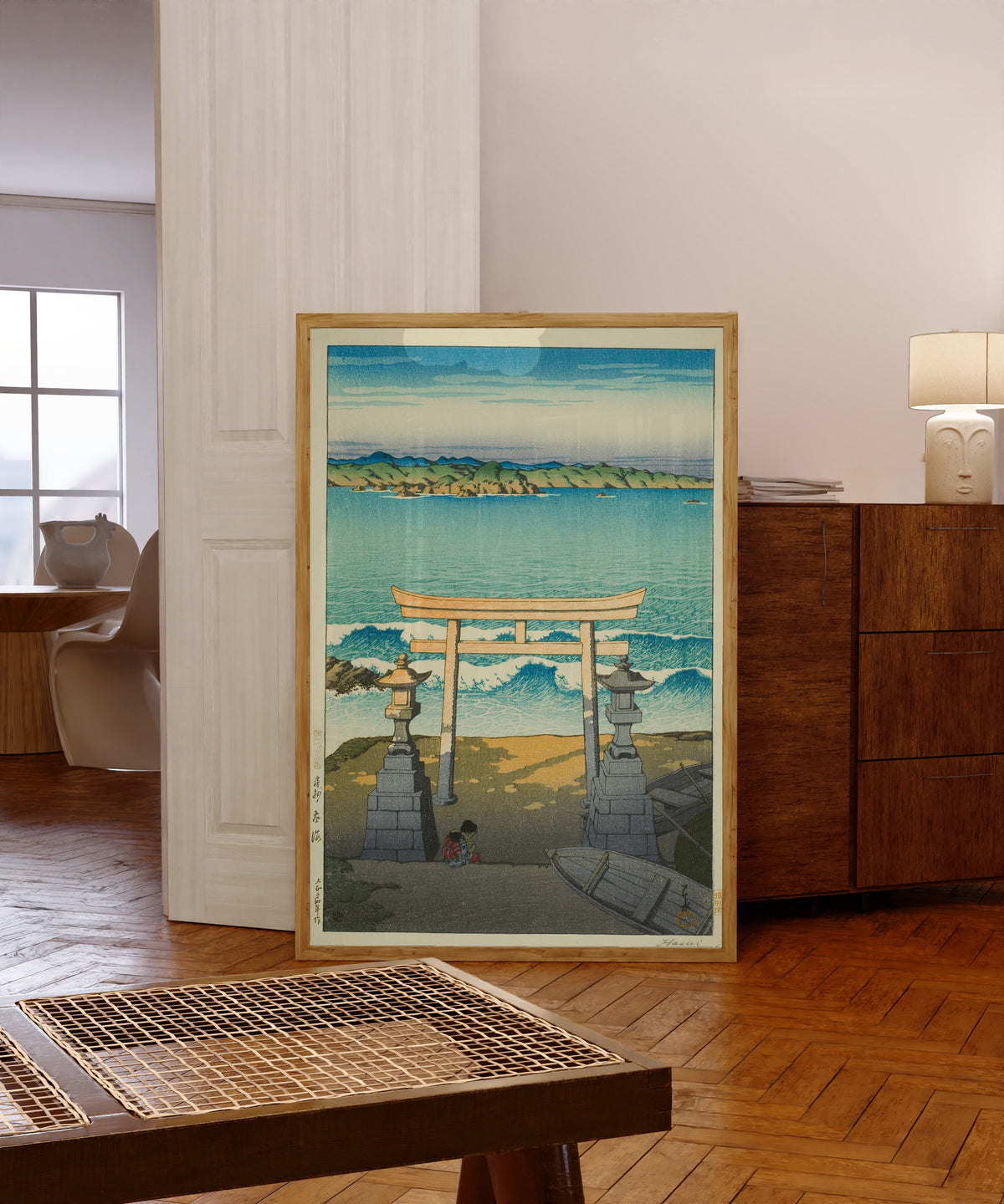 Framed art print of Pacific Ocean by Kawase Hasui, in a light wood frame leaning in a warm room with a parquet floor