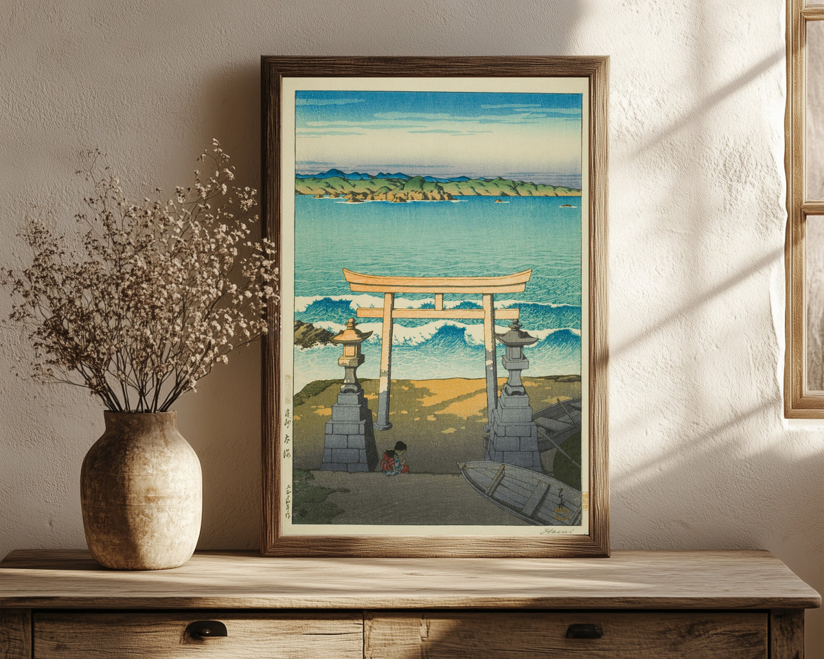 Framed art print of Pacific Ocean by Kawase Hasui, in a dark wood frame leaning on a rustic console beside dried flowers