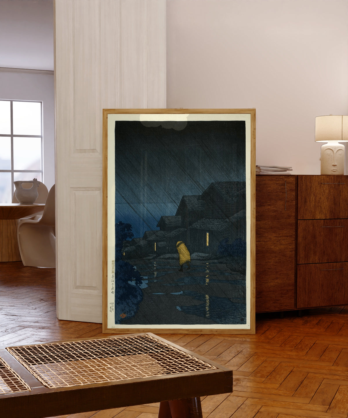 Framed art print of Rain at Teradomari Giclée Print: by Kawase Hasui, in a light wood frame leaning in a warm room with a parquet floor