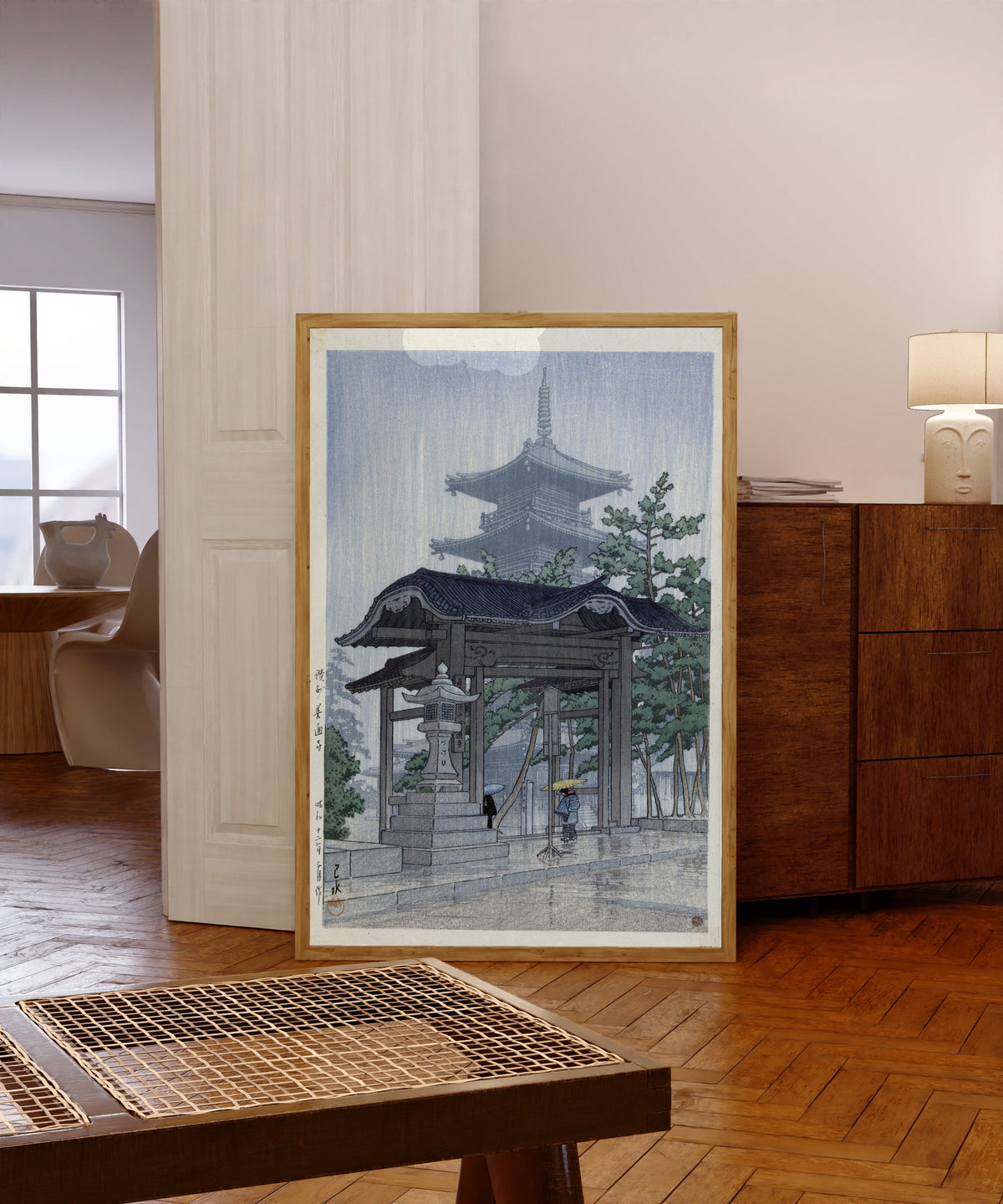 Framed art print of Zentsuji Temple, Sanuki, in Rain by Kawase Hasui, in a light wood frame leaning in a warm room with a parquet floor