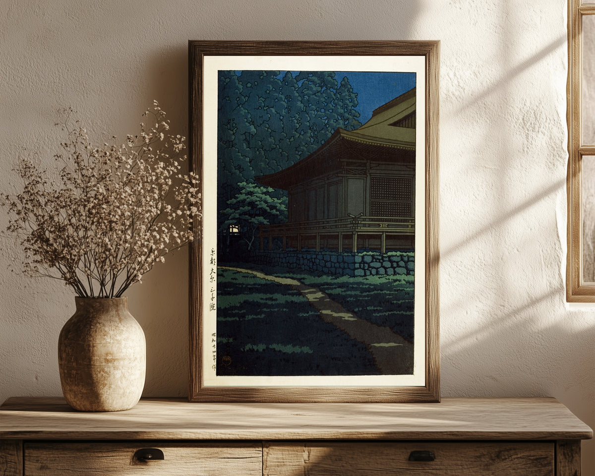 Framed art print of Sanzen-in Temple, Ohara, Kyoto by Kawase Hasui, in a dark wood frame leaning on a rustic console beside dried flowers