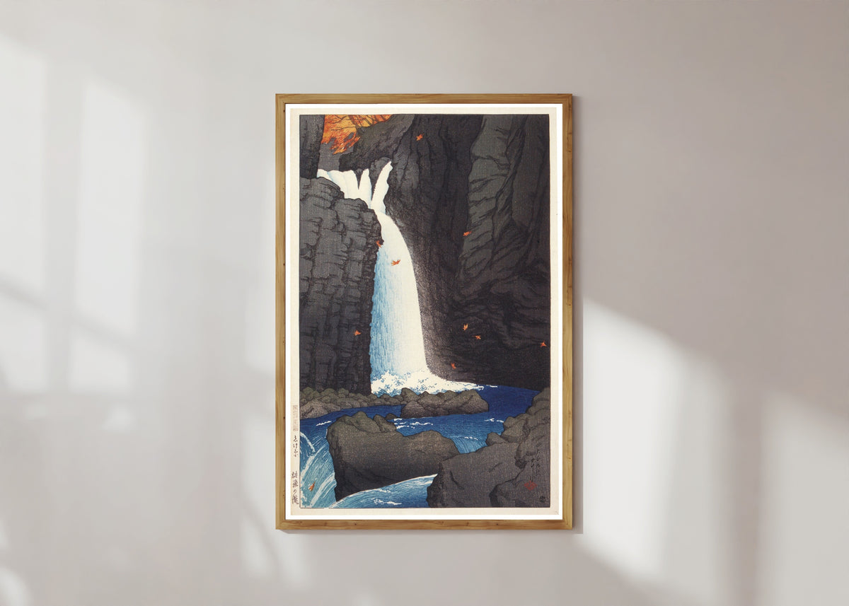 Framed art print of Shihohara Falls by Kawase Hasui, in a light wood frame on a sunlit white wall