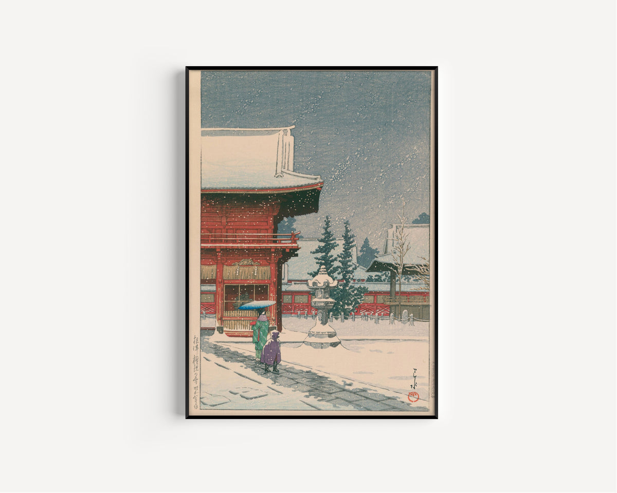 Framed art print of Snow at Nezu Gongen Shrine by Kawase Hasui, in a slim black frame on a plain white wall