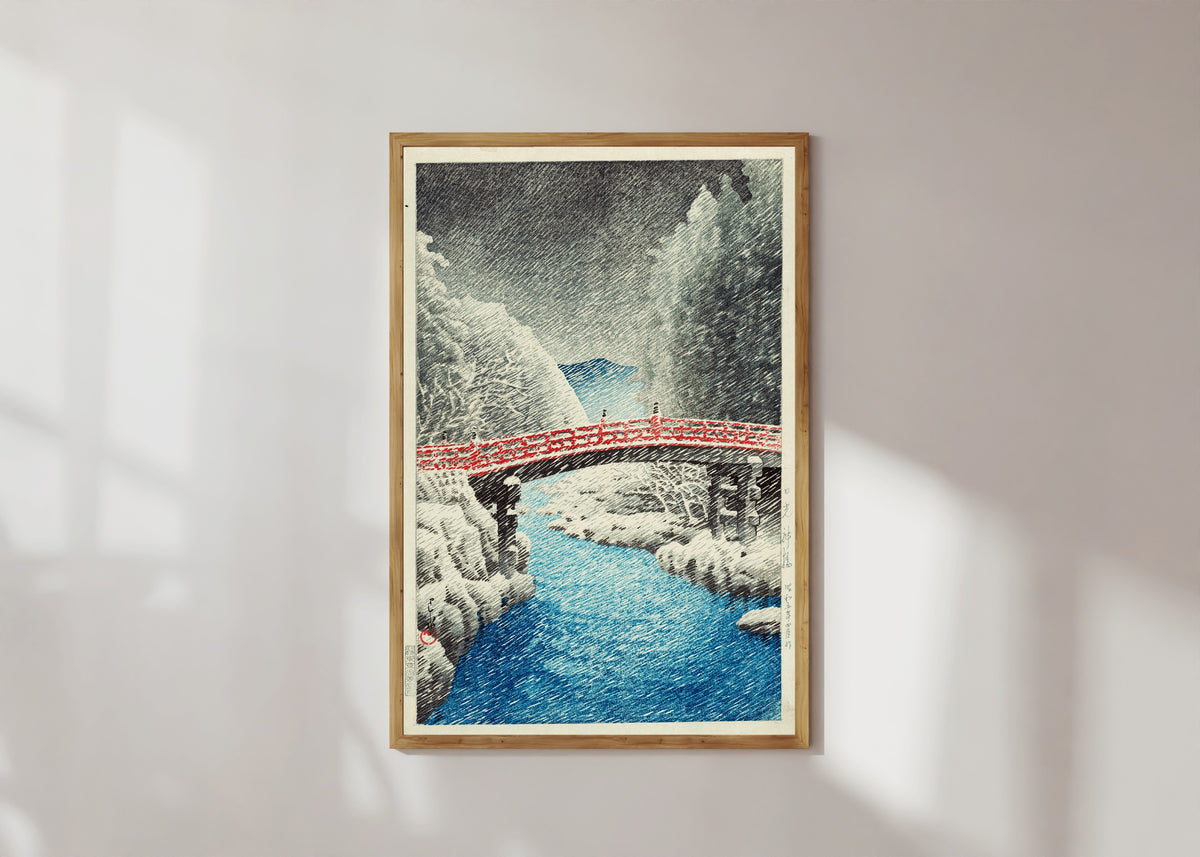 Framed art print of Snow at Shinkyo Bridge, Nikko by Kawase Hasui, in a light wood frame on a sunlit white wall