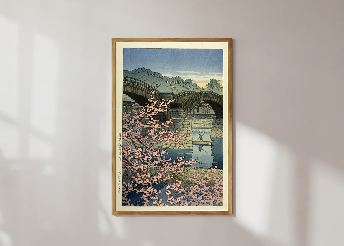 Framed art print of Kintai Bridge Cherry Blossoms by Kawase Hasui, in a light wood frame on a sunlit white wall